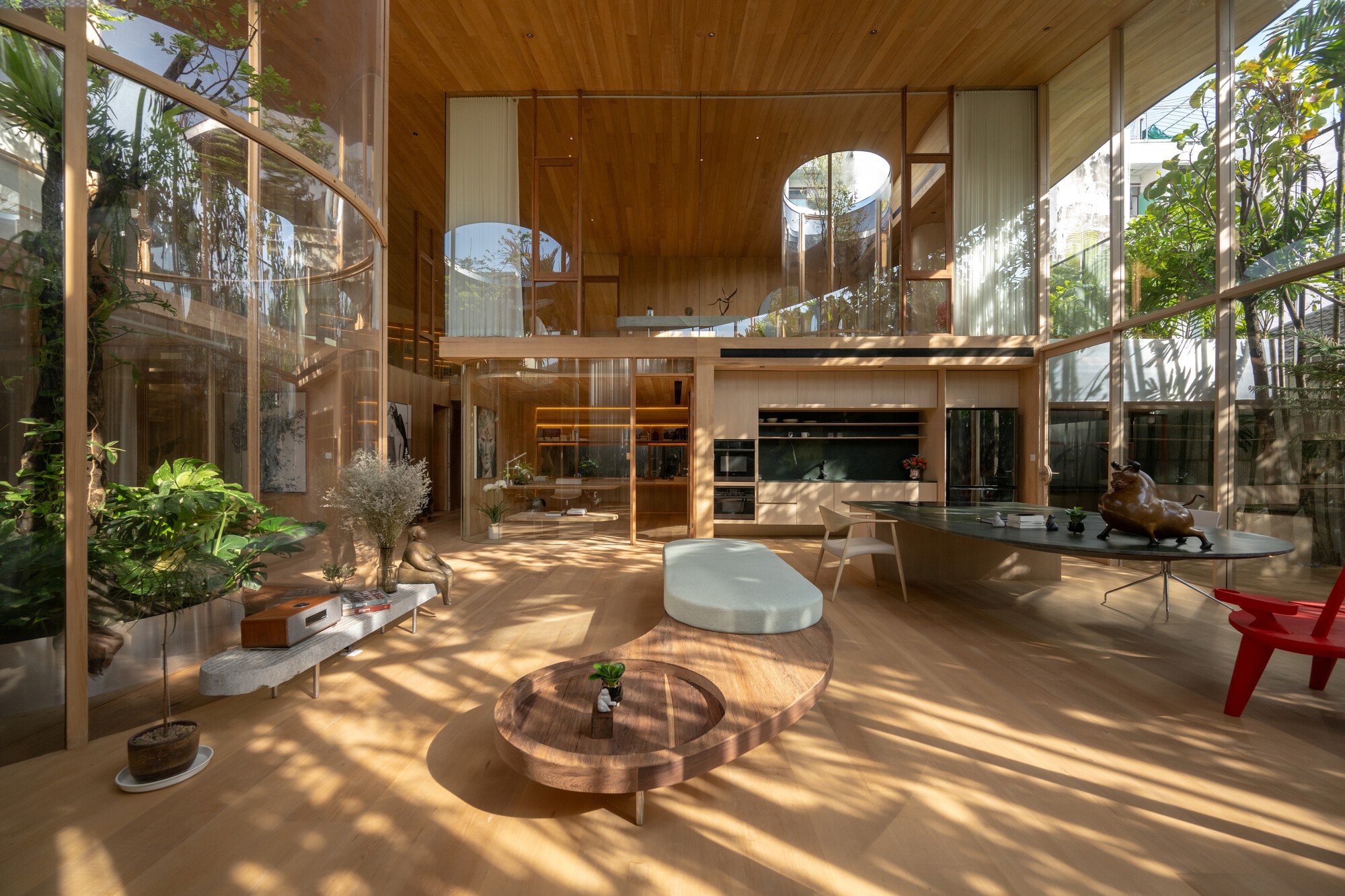 Double-height open-plan living room in Terrarium House with curved glass walls and a modern minimalist kitchen.