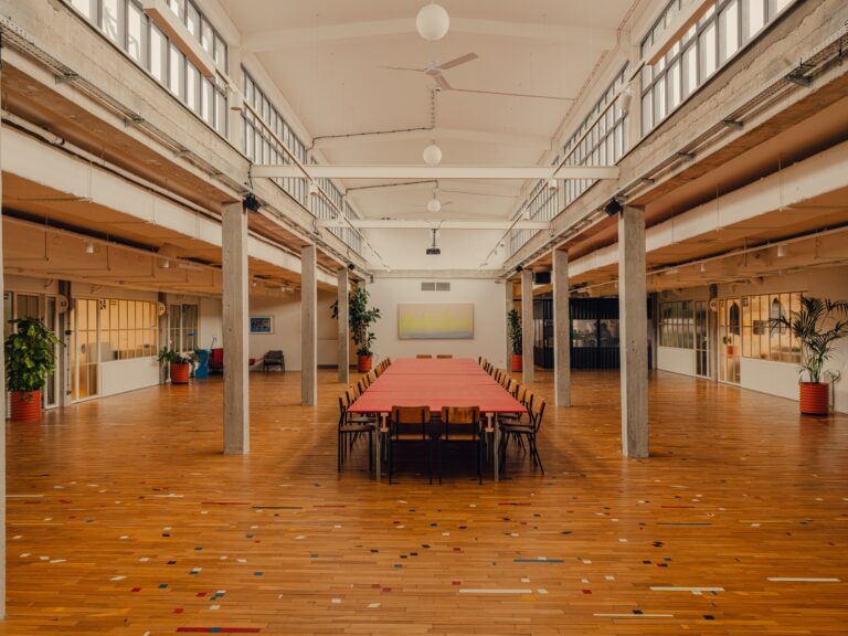 Large open-plan creative workspace in Grid Arthub Gdansk featuring reclaimed wooden flooring and industrial columns.