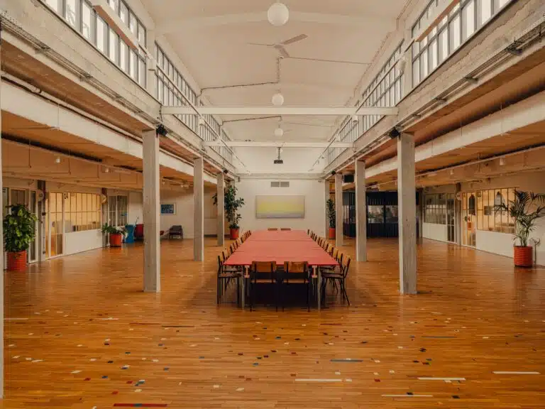 Large open-plan creative workspace in Grid Arthub Gdansk featuring reclaimed wooden flooring and industrial columns.