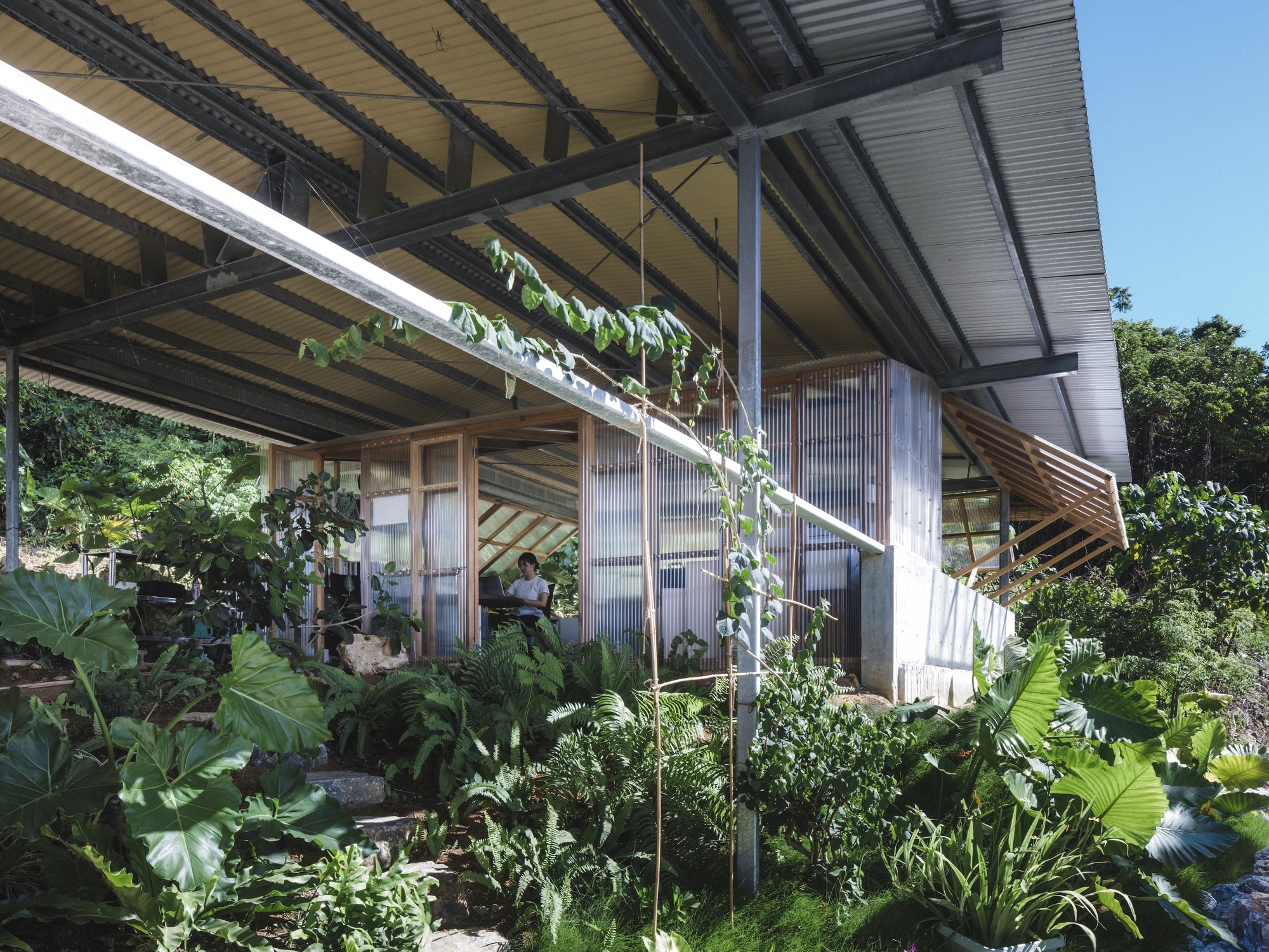Exterior view of the Okinawa architectural office featuring a double-layered structure with insect mesh and folding vinyl panels.