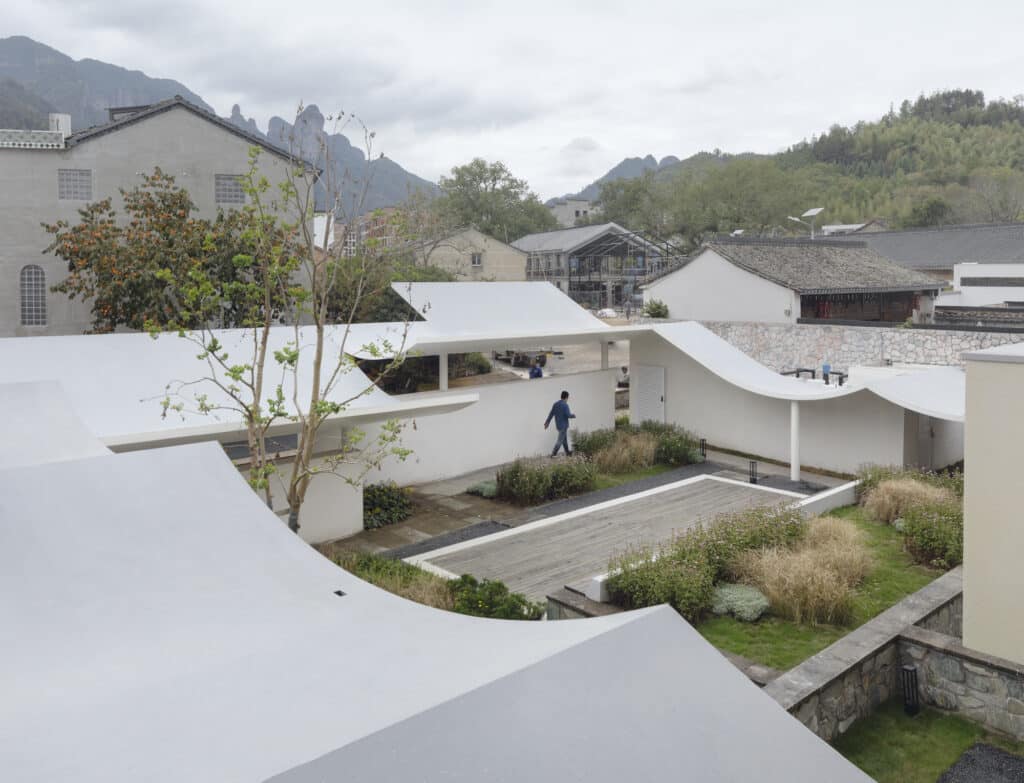 Bird's-eye view of the inner courtyard at Qingyi Lodge featuring undulating white roofs and landscaped gardens.