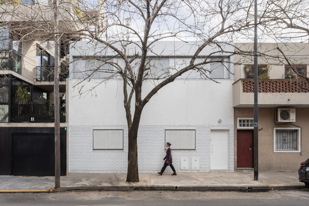 Exterior facade of a renovated PH unit in Buenos Aires with a minimalist white finish and integrated upper expansion by Estudio Yama.