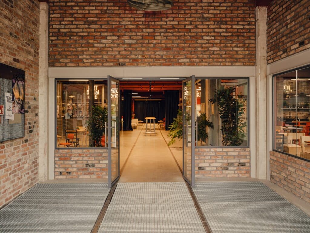 Industrial entrance of Grid Arthub with original brickwork and modern glass doors leading to the interior hub.