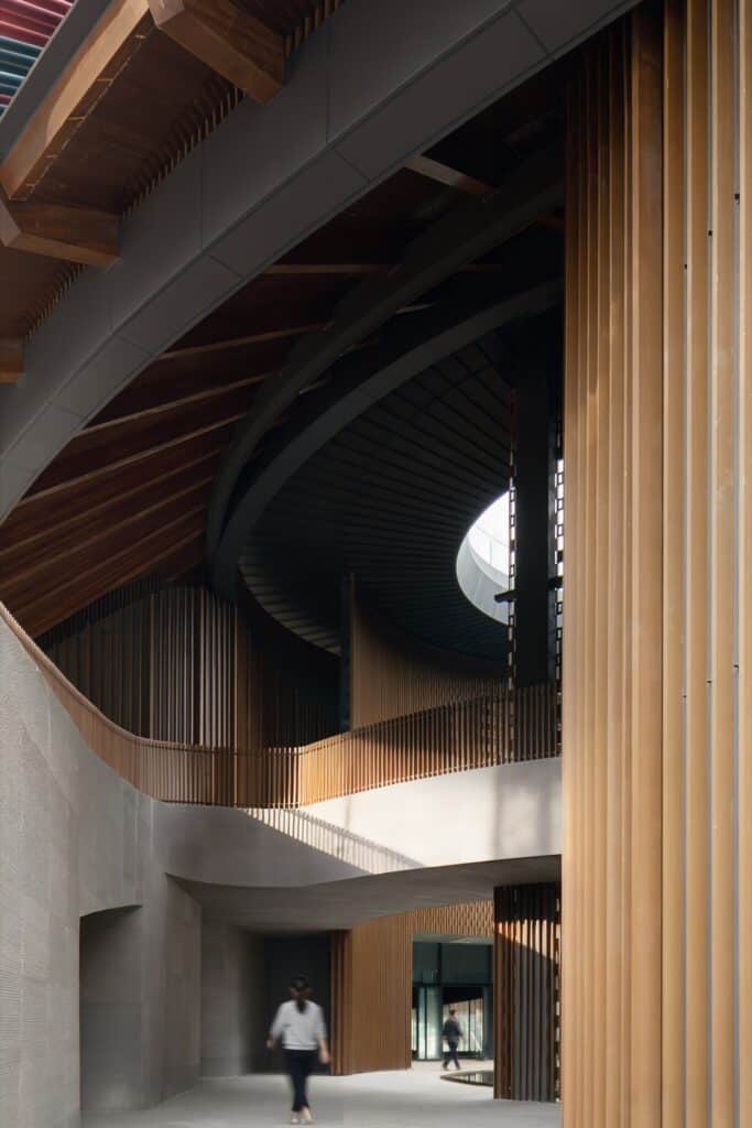 Interior view of the museum's circulation path featuring Glulam wooden structures and vertical grilles.