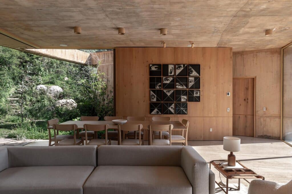 Interior dining and living room with concrete ceilings, wooden wall panels, and artistic eye-themed portraits.