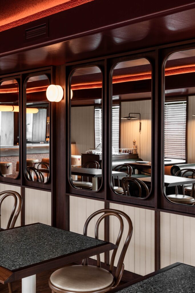 Arched mirrored wall partitions reflecting the dining area and wooden furniture in a modern Toronto pizzeria.