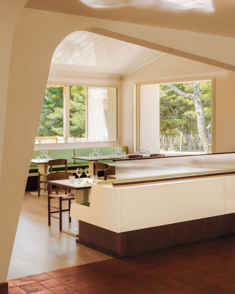 Dining area at Le Belv&eacute;d&egrave;re restaurant with large windows overlooking the pine forest of Provence.