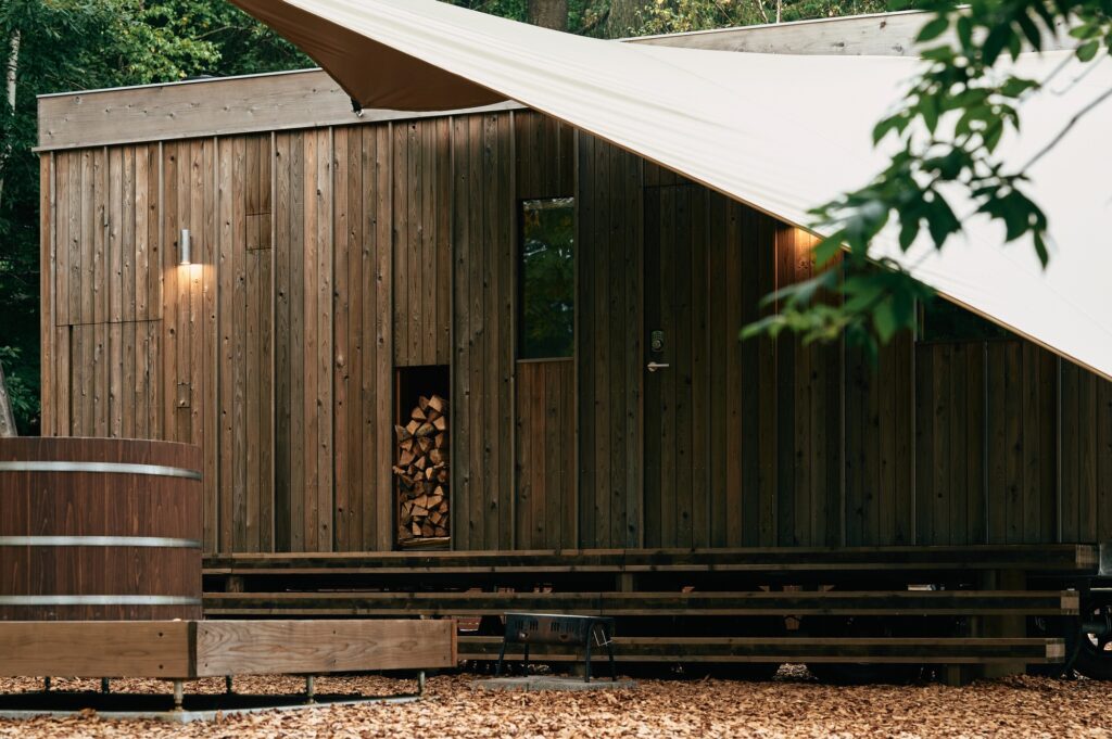 Close-up of the Earthboat Cave wooden facade featuring vertically arranged Japanese cedar planks, a wood storage niche, and a sleek entrance door.