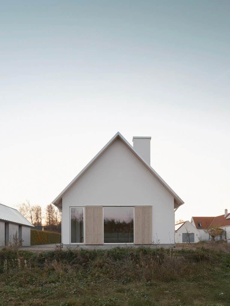Side gable view of Rorum House showing the steep pitch and wooden slat window coverings.