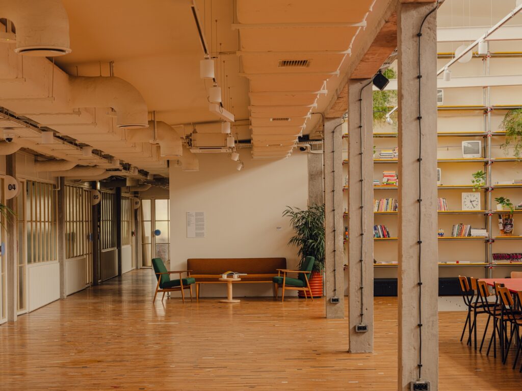 Creative studio lounge at Grid Arthub with vintage furniture and exposed ceiling ventilation systems.