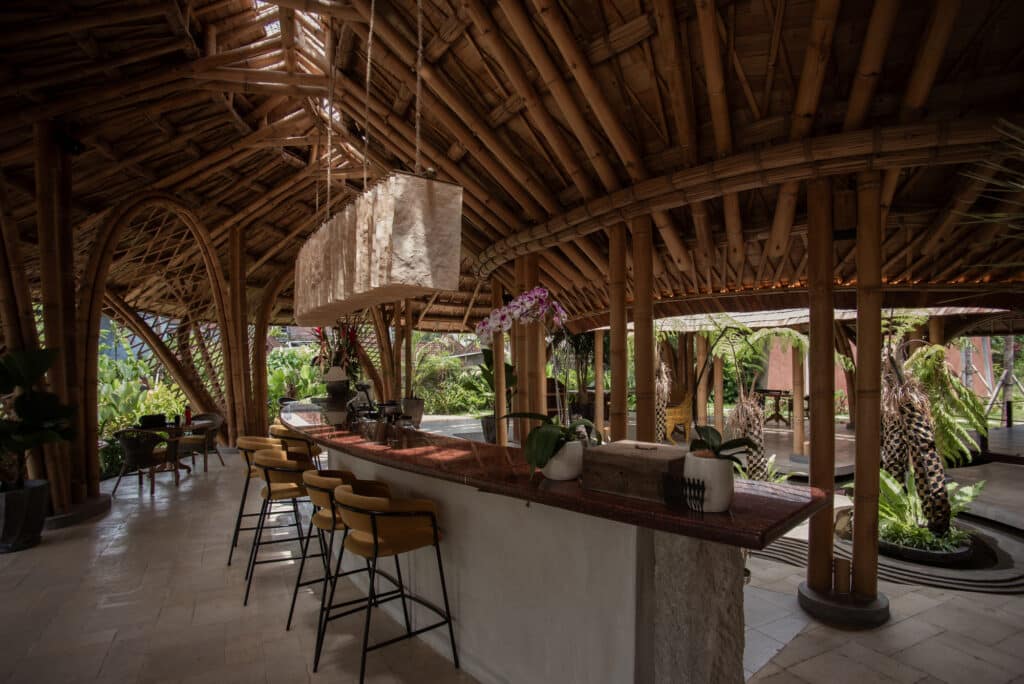 Bamboo bar counter at Juna Ubud with traditional lighting and arched bamboo structures.