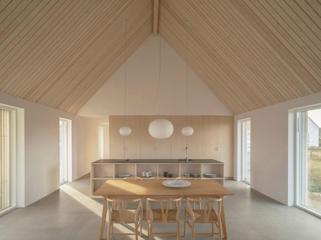 Modern open-plan kitchen and dining area in Rorum House featuring custom ash woodwork and minimalist pendant lighting.