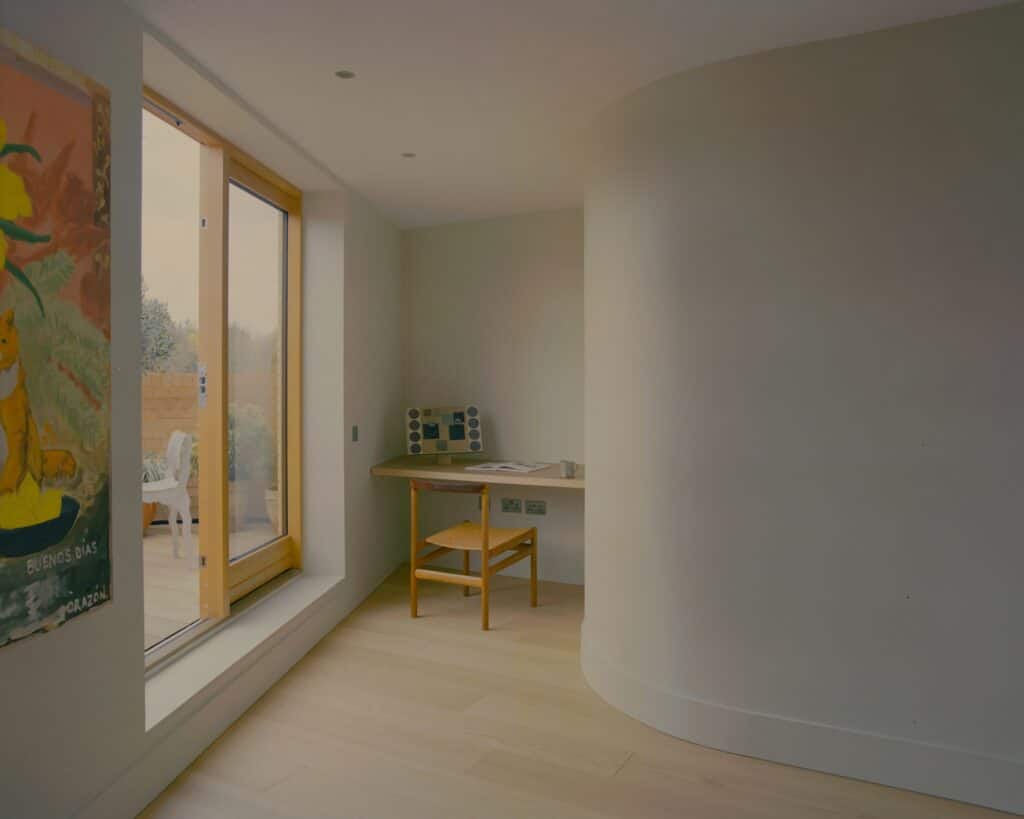 Interior study nook in Runda House with a curved white wall and a large glass door leading to a terrace.