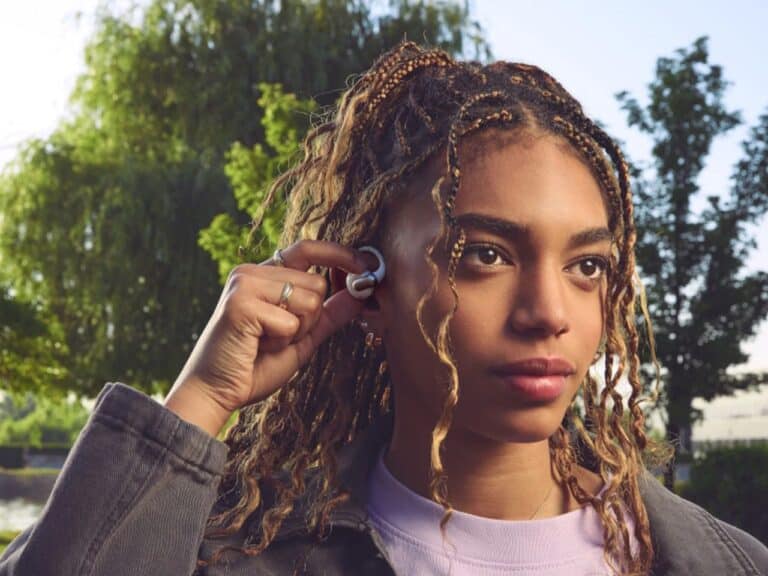 Close-up of a user adjusting the JBL Sense Pro open-ear earbud featuring a flexible ear hook for a secure fit during exercise.