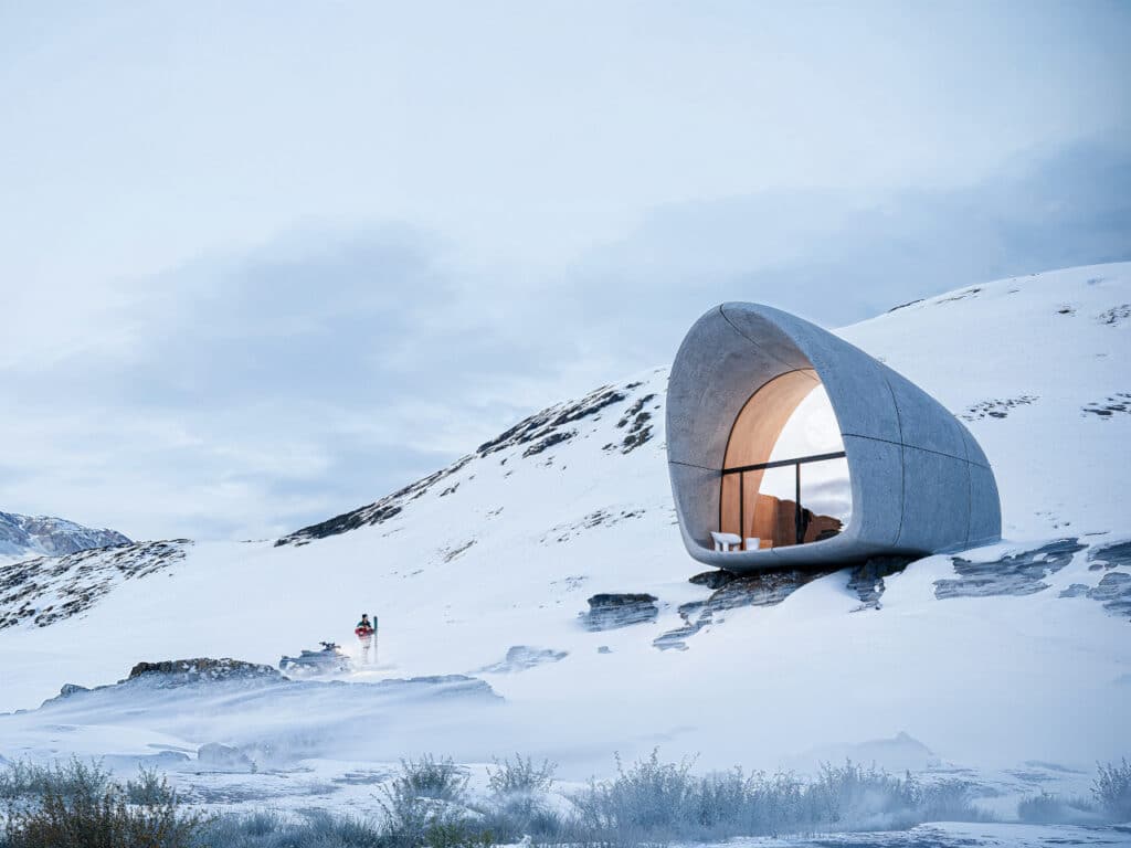 AltiHut mountain cabin on a snowy slope with a snowmobile and climber in the foreground.
