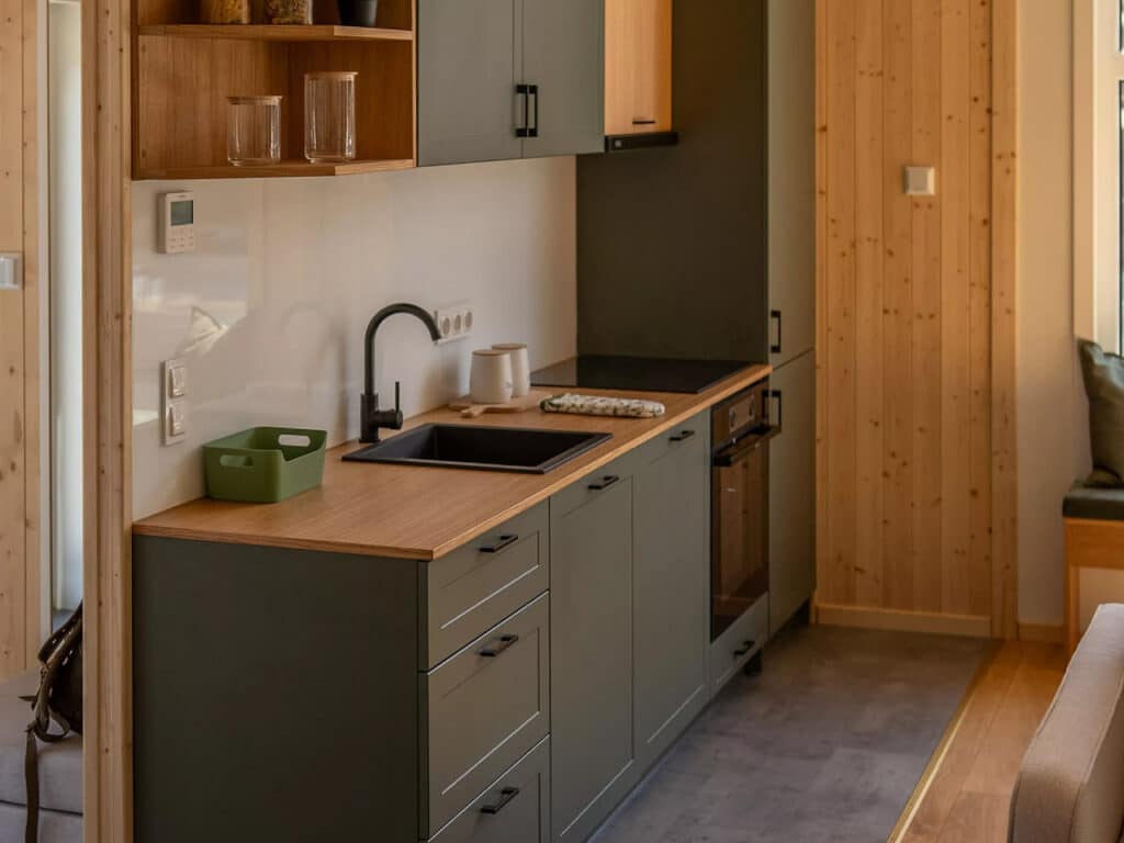 Close-up of minimalist kitchen workstation with a black faucet, built-in induction cooktop, and wooden surfaces.