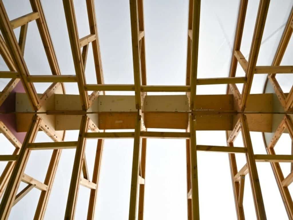 Interior low-angle view of the Arkhive pavilion's geometric timber lattice and roof structure.