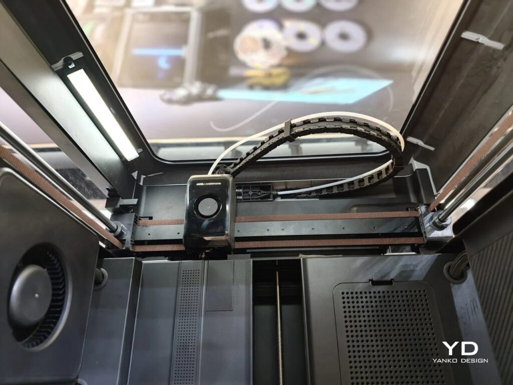 Top-down view of the 3D printer nozzle head moving along the X-axis rail with integrated lighting.