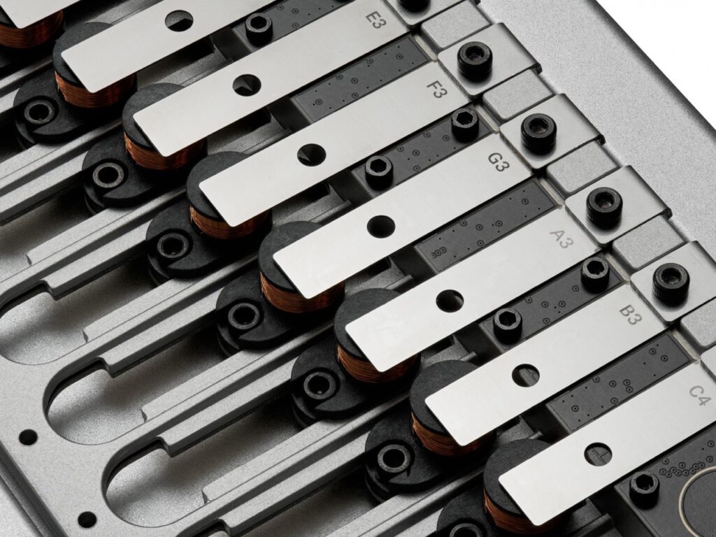 Macro photography of the Korg Phase8 resonator bars, labeled with musical notes such as E3, F3, and G3, showing the precision-engineered metal components.