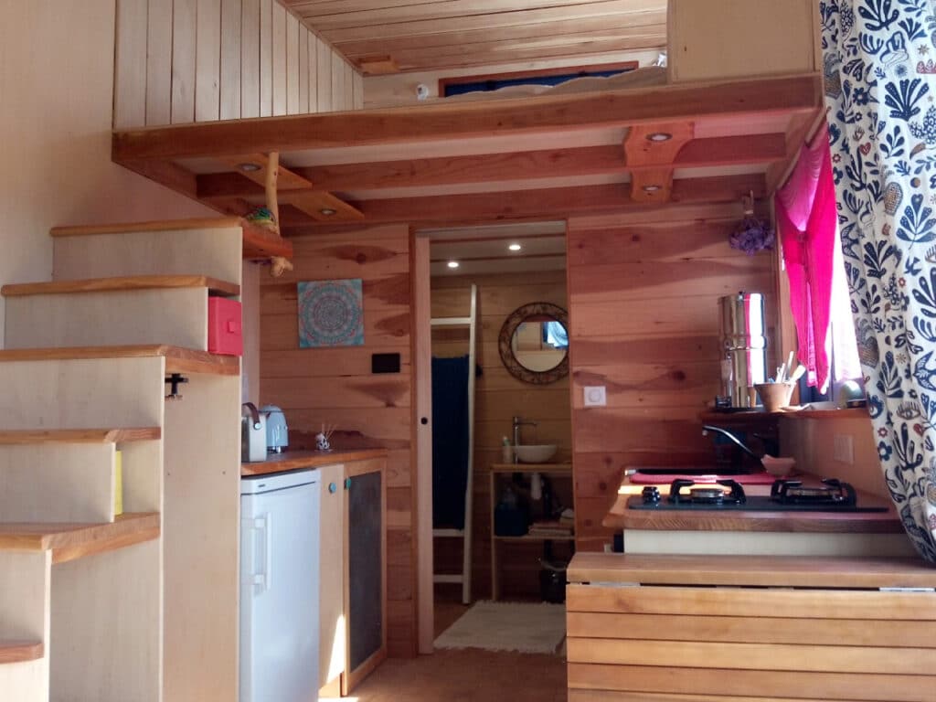 Interior architectural view showing the multifunctional staircase, kitchen counter, and the entrance to the bathroom.