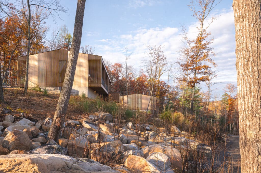 Modern architectural detail of Sera project villas integrated into a rocky terrain with dense autumn forests in West Virginia.