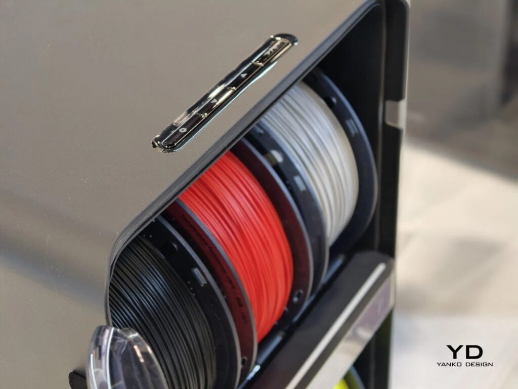 Macro shot of black, red, and white 3D printing filament spools inside the AtomForm Palette 300 storage unit.