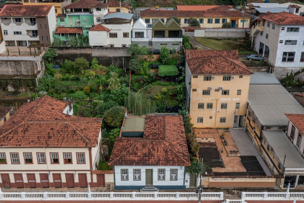 Aerial view of Heloisa and Leonardo House showing the traditional clay tile roofs and the contemporary terraced garden expansion in a dense urban heritage context.