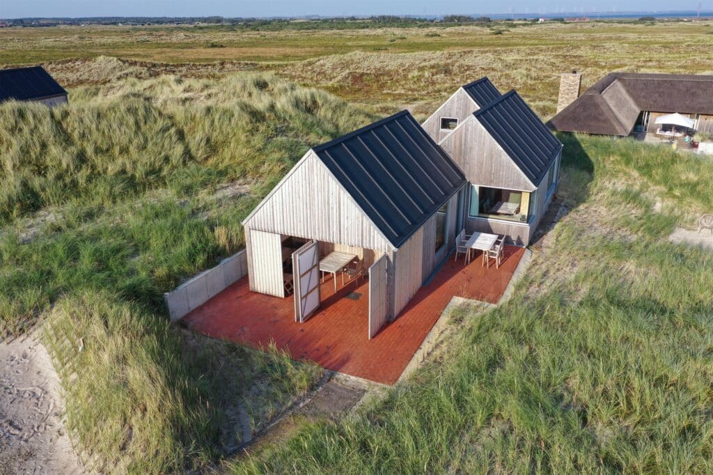 Aerial view of Kligwood Summer House showing its pitched roof modules integrated into the coastal dune vegetation.