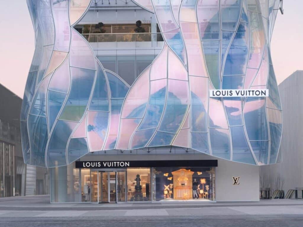 Full-height view of the Maison Louis Vuitton Sanlitun storefront at street level, showing the dichroic properties of the glass panels.