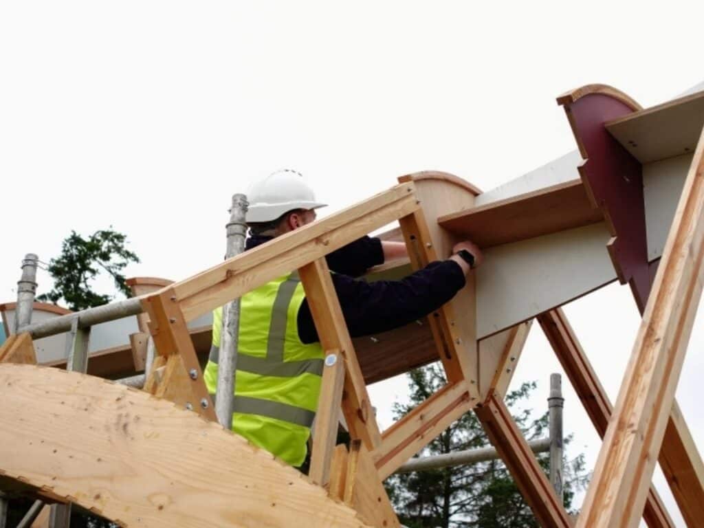 Close-up of a worker installing reversible timber joints on the Arkhive pavilion structure.
