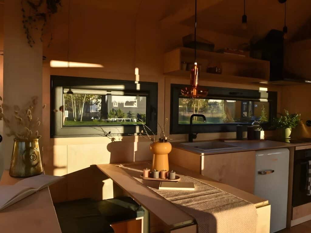 Julia tiny home interior during sunset, showing warm light hitting the plywood walls and dining table.