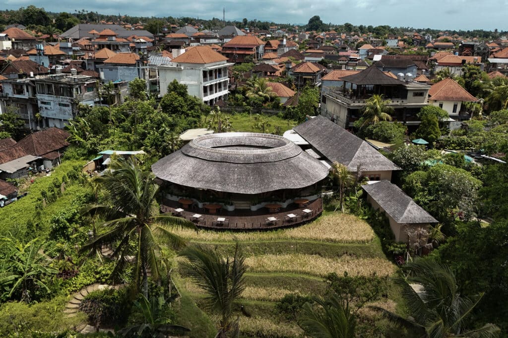 High-angle shot of Guna restaurant's tiered roof amidst Ubud's dense urban and natural landscape.