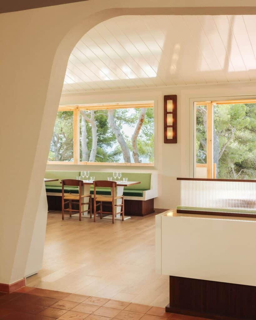 Wide view of the restaurant interior showing the transition from terracotta to wooden flooring and scenic outdoor views.