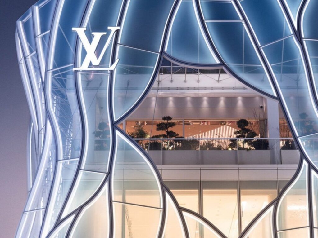 Close-up of the upper floors of the LV Beijing Maison, showing the integration of greenery on the terrace behind the translucent glass skin.