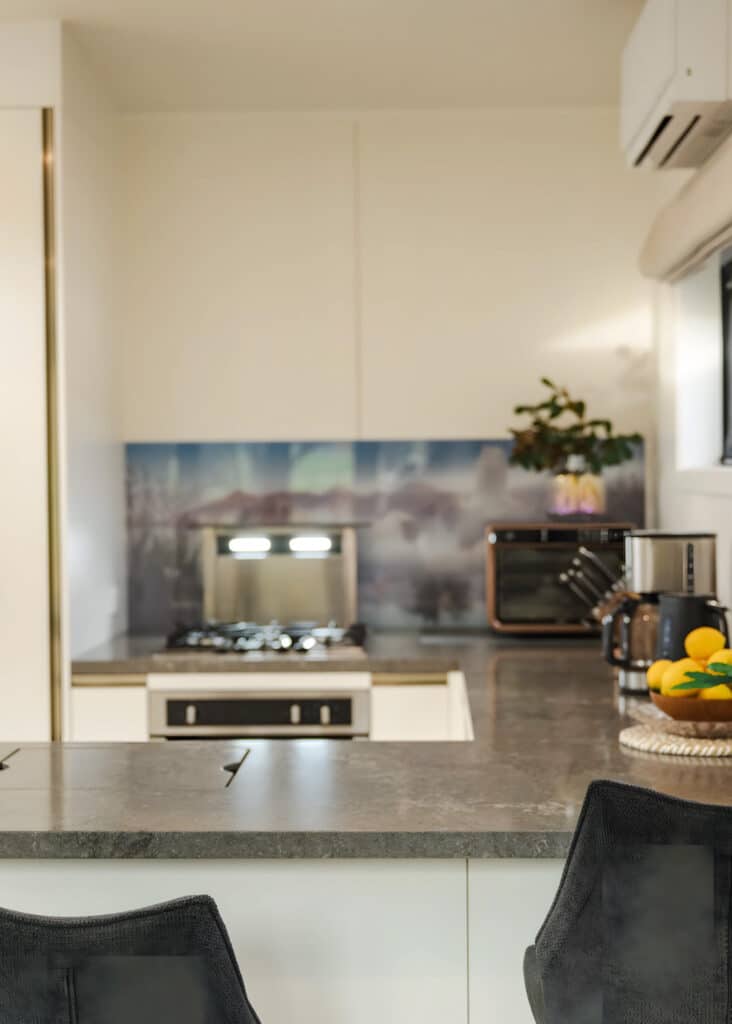 Close-up of a modern tiny house kitchen featuring a stone breakfast bar and high-end appliances.