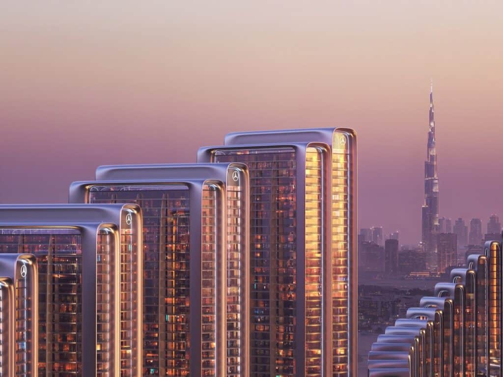 Close-up of the upper floors of Mercedes-Benz branded towers in Dubai with the Burj Khalifa visible in the background during twilight.