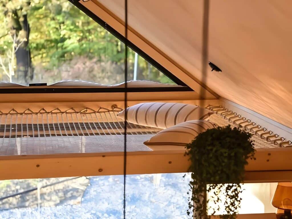 Close-up of pillows on the net mezzanine in Julia tiny home near a triangular skylight window.