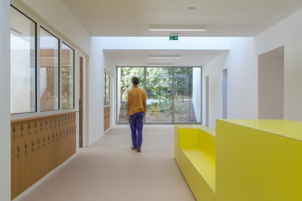 Modern interior hallway of the school with a view towards a green landscape through large glass doors.