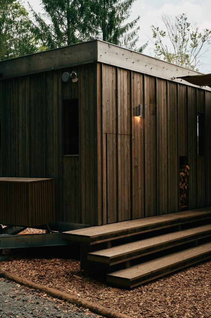 Perspective view of the Earthboat Cave corner showing the mobile chassis and the weathered texture of the Japanese cedar cladding.