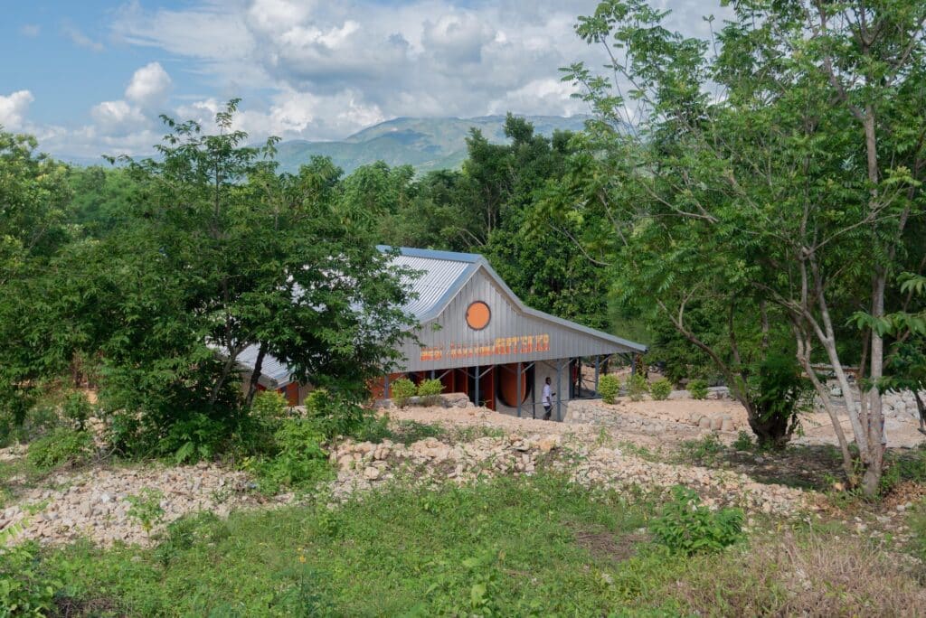 Distant view of the community center nestled among trees with the mountains of southern Haiti in the background.