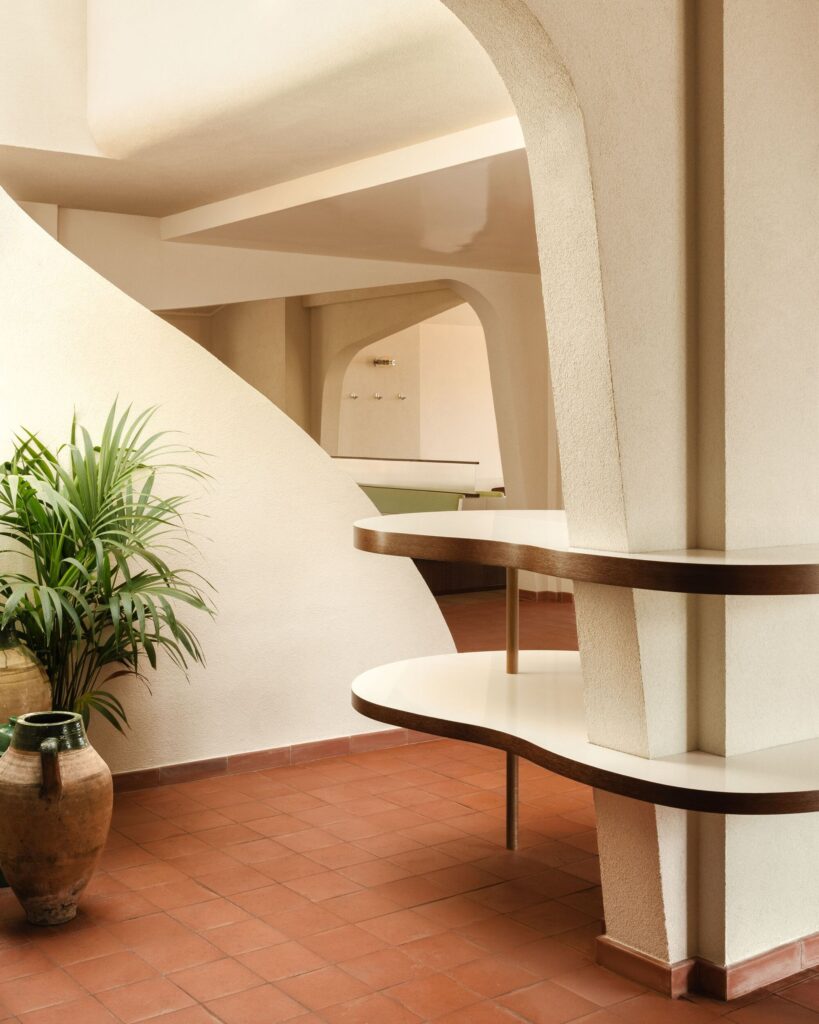 Interior detail of Le Belv&eacute;d&egrave;re restaurant featuring hand-drawn curved walls, terracotta flooring, and organic shelving units.