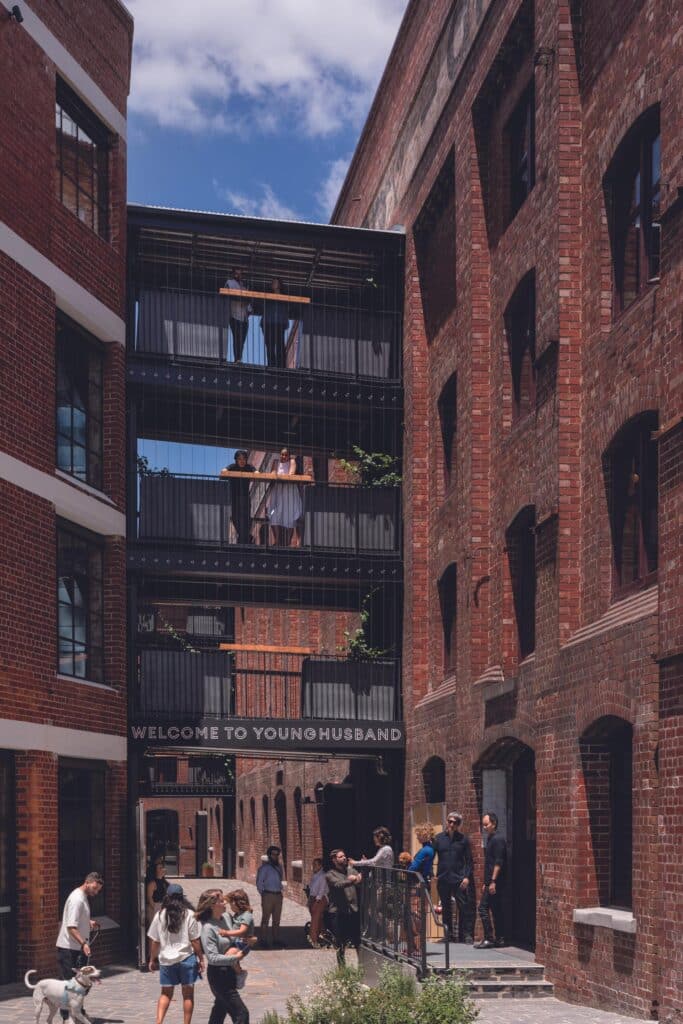Entrance to the Younghusband precinct with "Welcome to Younghusband" signage and pedestrians walking through a revitalized industrial courtyard.