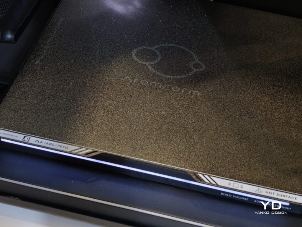 Detailed close-up of the AtomForm Palette 300 heated build plate featuring the brand logo and filament compatibility indicators for PLA, ABS, and PETG.
