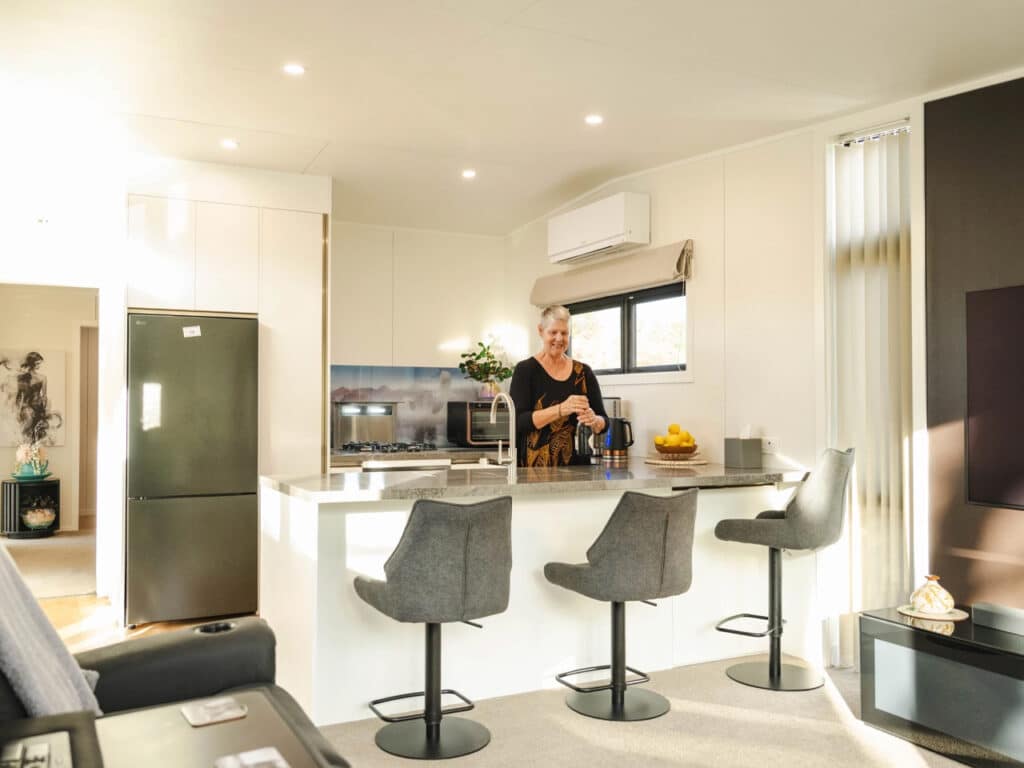 Woman preparing a drink in the modern kitchen of the Bespoke Base tiny house.