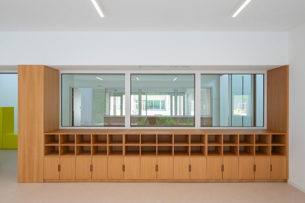 Built-in wooden storage units and large windows in a Paul Doumer School classroom.