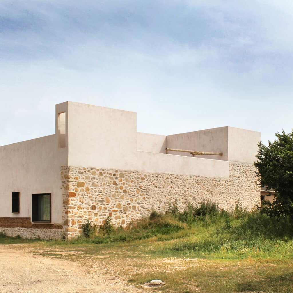 Angular exterior view of the house in Riaza showing the tower-like structure and mixed-material construction.