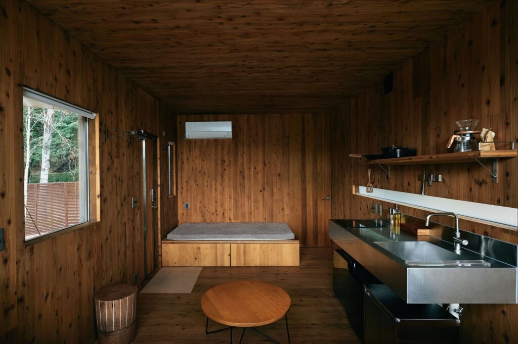 Interior view of Earthboat Cave cabin featuring a stainless steel kitchen counter, wooden walls, and a minimalist sleeping platform.