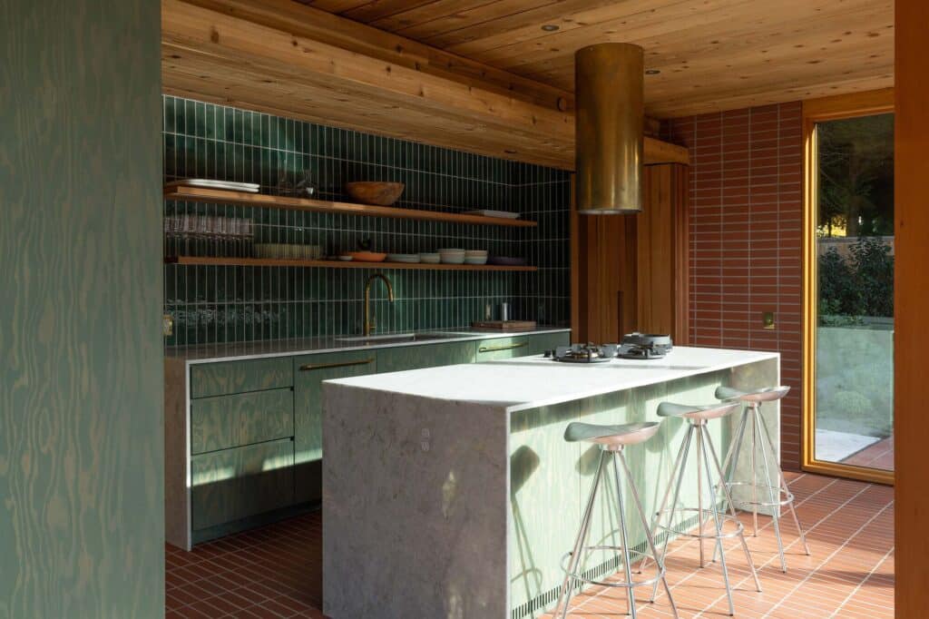 Contemporary kitchen with green stained Douglas fir cabinetry, a marble island, and a brass cylindrical vent hood.