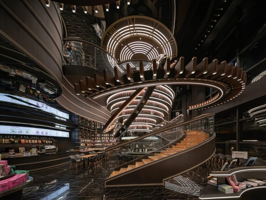 Wide-angle view of the central staircase and illuminated orbital structures in Huai&rsquo;an Zhongshuge with a view of the caf&eacute;.