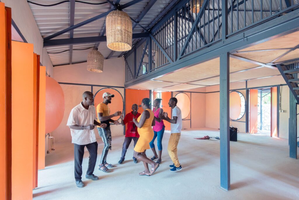 Local residents dancing in the multipurpose hall of the community center, showing the vibrant social life and interior steel structure.